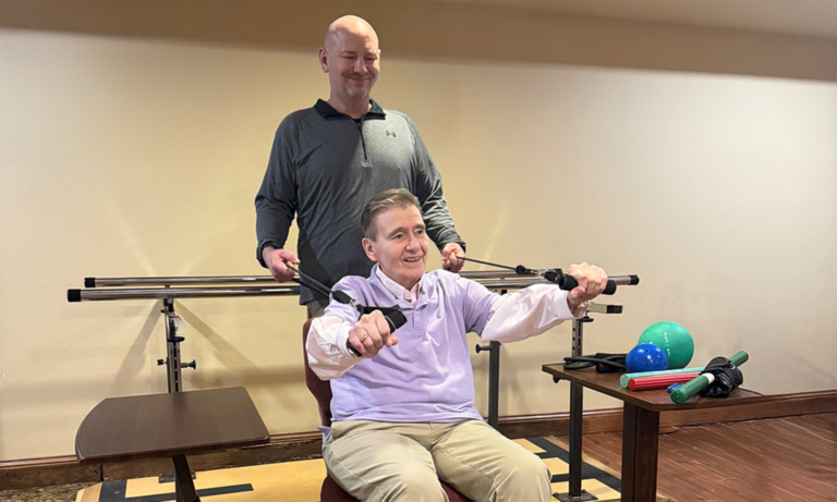 Occupational therapist guiding a seated patient through a stretching exercise.